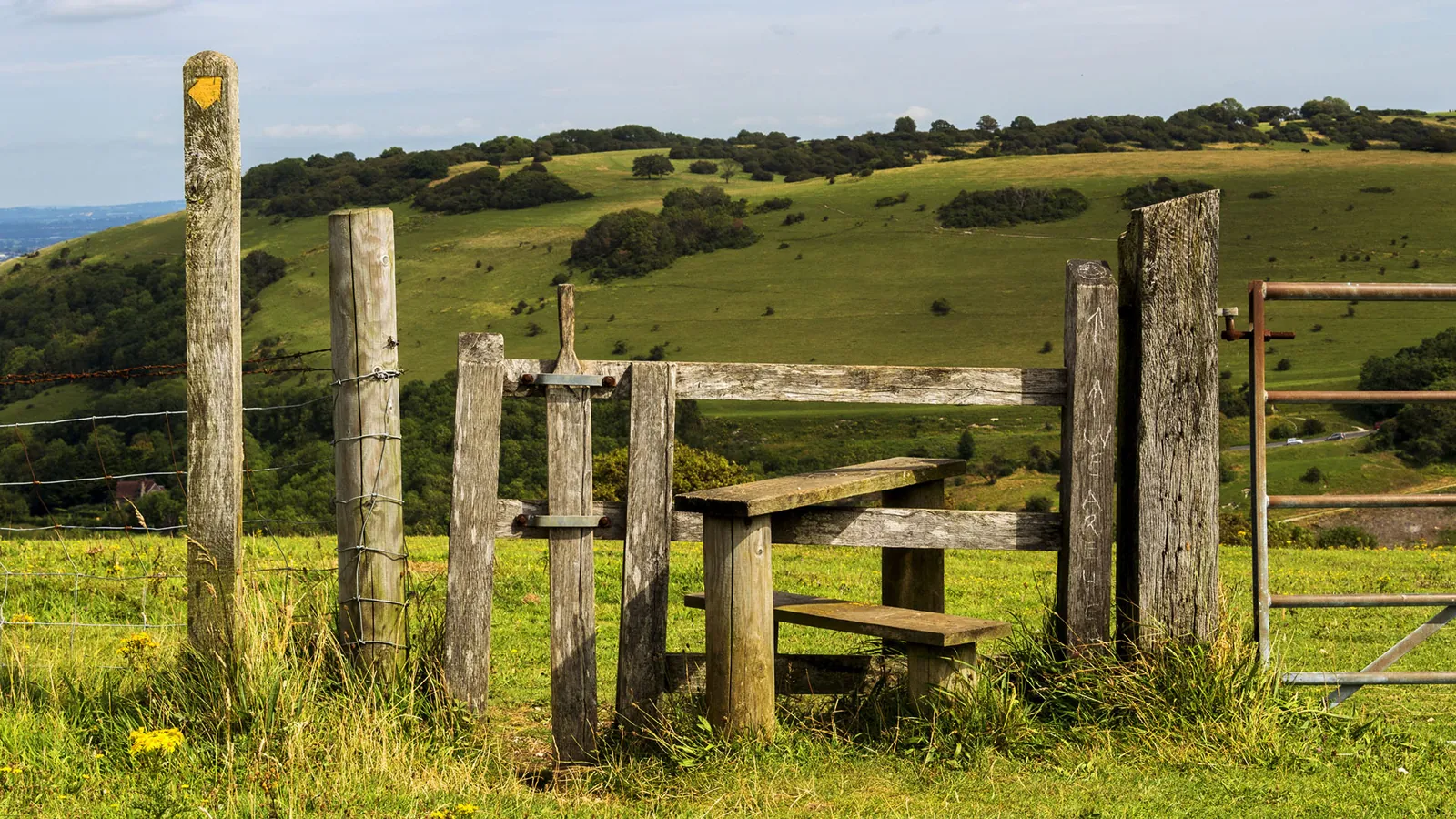 A weathered wooden stile and gate on green downland